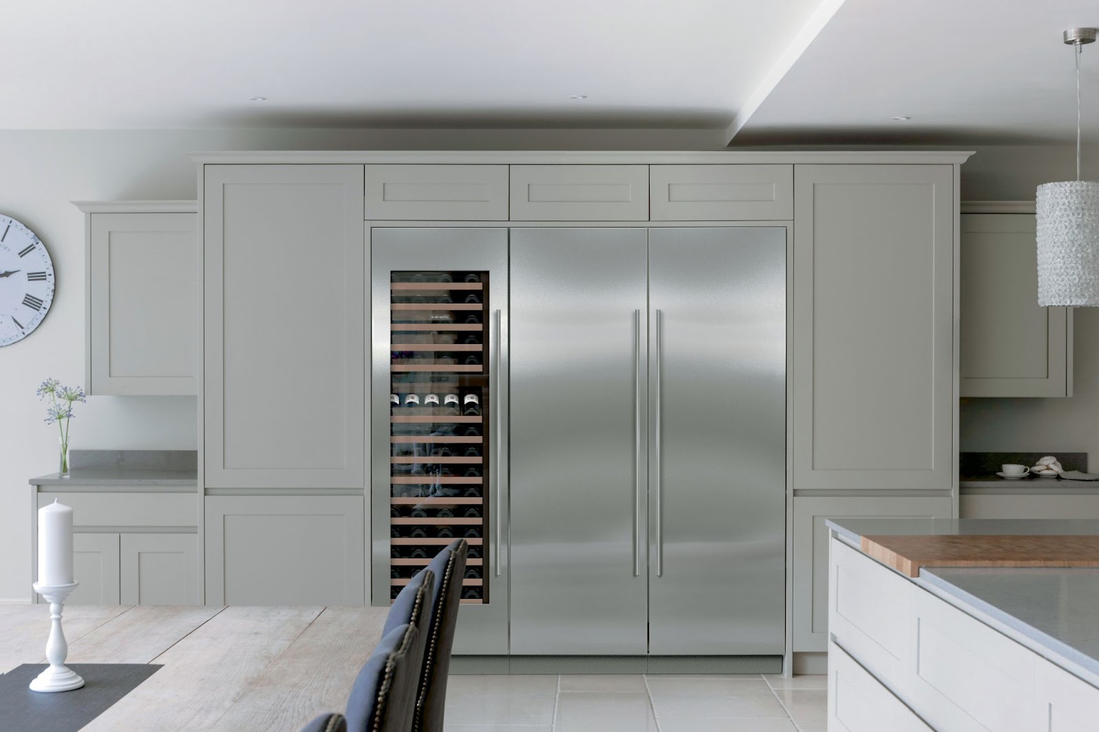 Modern kitchen with built-in stainless steel refrigerator, wine cooler, light gray cabinets, and minimal decor including a wall clock and candles—perfect for discovering how to clean the filter on a Cove dishwasher.