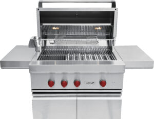 Large stainless steel outdoor grill with four red control knobs, open lid, side shelves, and interior lights, shown on a white background.